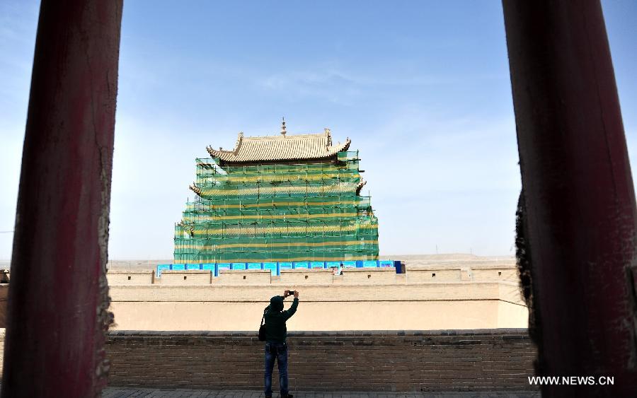 A tourist takes photos of the Jiayu Pass, the starting point of a section of the Great Wall constructed during the Ming Dynasty (1368-1644), which is under repair, in Jiayuguan City, northwest China's Gansu Province, April 16, 2013. China will pour 2.03 billion yuan (about 328 million US dollars) in maintaining the Jiayu Pass, also including the construction of a world culture heritage inspection center and a heritage protection and display project. Built in 1372, the Jiayu Pass also served as a vital passage on the ancient Silk Road. It was listed on UNESCO's World Heritage List in 1987. (Xinhua/Lian Zhenxiang) 