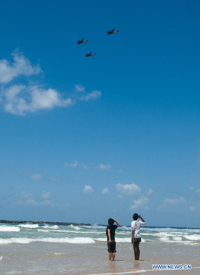 Children watch the performance of aerobatic flights by Israeli aircrafts above the Mediterranean Sea near Tel Aviv during a celebration for Israel's Independence Day, April 16, 2013. Beginning at sundown Monday and ending at sundown on Tuesday, Israel celebrated its Independence Day marking the country's 65th anniversary. (Xinhua/Han Chong) 