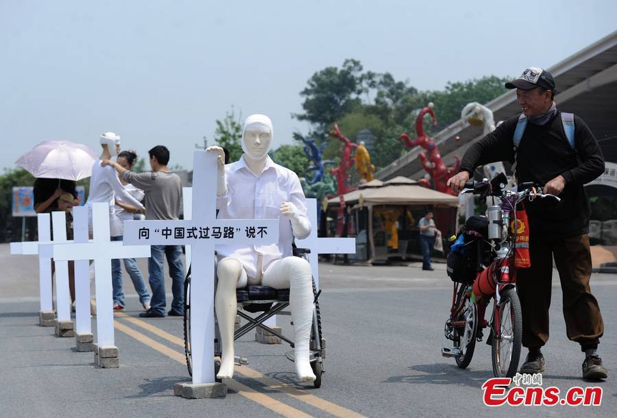 Crosses with words "say no to Chinese-style street crossing" are erected around two mannequins bound by bandage in street of downtown Chongqing, April 16, 2013. The installation warned people to obey traffic regulations. (CNS/Chen Chao)
