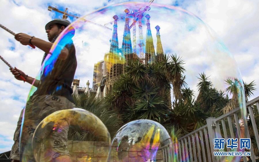 A busker performs making big soap bubble in front of the Sagrada Familia in Spain’s Barcelona on April 10. (Xin Hua/Sun Wen)