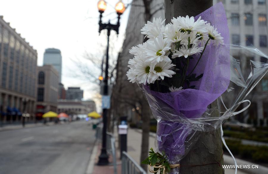 Flowers for the victims in Boston Marathon blasts are seen at the blast scene in Boston, the United States, April 16, 2013. The death toll has risen to three, with 176 people injured. (Xinhua/Wang Lei) 