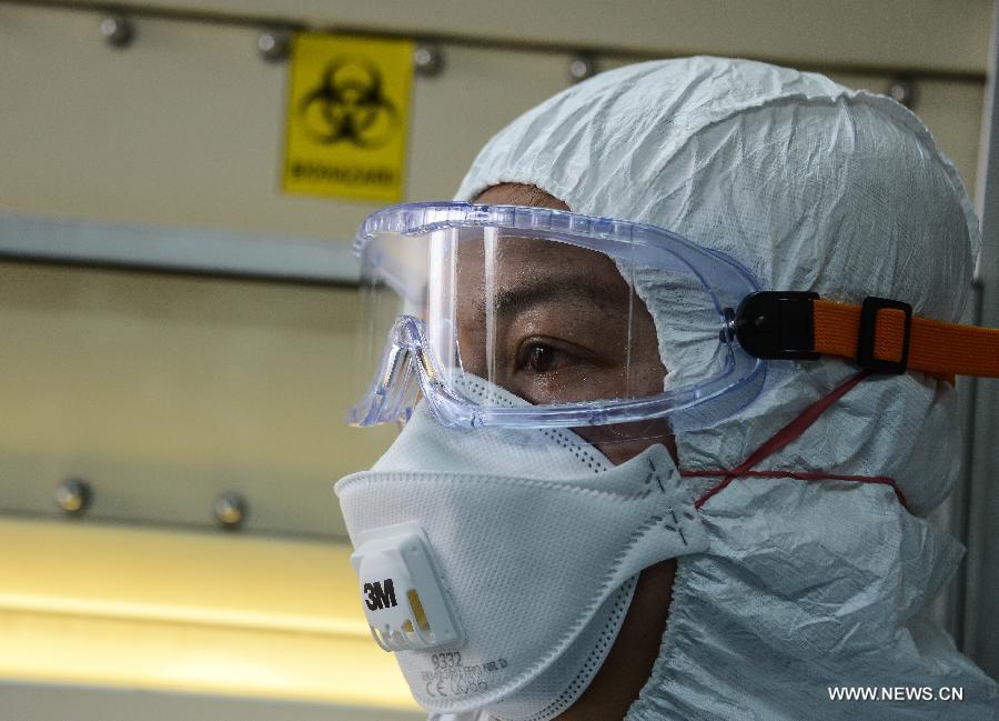 Dr. Chen Yin, a researcher at the provincial center for disease control and prevention, sweats after testing samples of a suspected case of the H7N9 avian influenza virus, in Hangzhou, capital of east China's Zhejiang Province, April 17, 2013. An emergent testing team on 24-hour stand-by was set up in the center after the recent spread of the H7N9 virus. Infections within the province will be officially confirmed by the center. (Xinhua/Xu Yu)