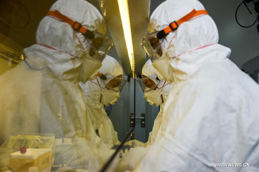 Researchers in protective suits test samples of a suspected case of the H7N9 avian influenza virus at the provincial center for disease control and prevention in Hangzhou, capital of east China's Zhejiang Province, April 17, 2013. An emergent testing team on 24-hour stand-by was set up in the center after the recent spread of the H7N9 virus. Infections within the province will be officially confirmed by the center. (Xinhua/Xu Yu)