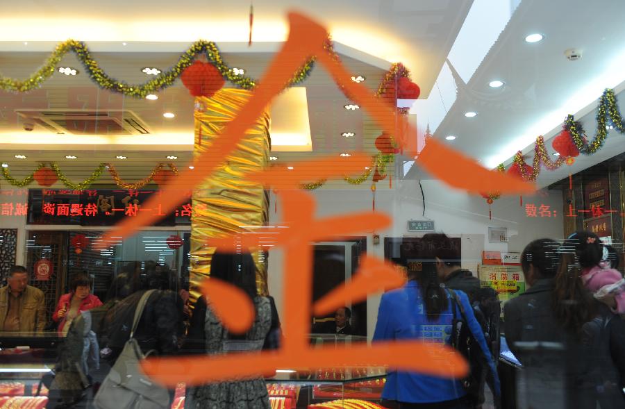 A Chinese character is stuck on the glass at a gold jewellery shop in Wuxi, east China's Jiangsu Province, April 18, 2013. Gold jewellery shops through China have lowered price of gold jewellery due to the consecutive decline of gold price global markets recently, which boost sales in these shops. (Xinhua/Zhang Liwei) 