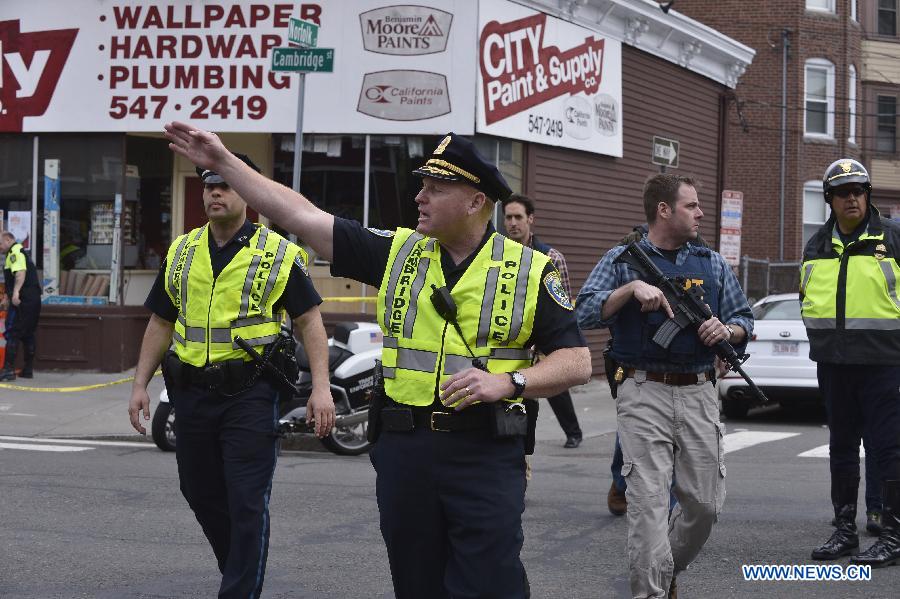 Policemen search for suspect in Camebridge neighbourhood of Boston, Massachusetts, April 19, 2013. Two men sought in the Boston Marathon bombing killed a police officer, wounded another in a firefight and hurled explosive devices at police during their getaway attempt in a night of violence that left one suspect dead and the other on the loose early Friday. (Xinhua/Zhang Jun) 