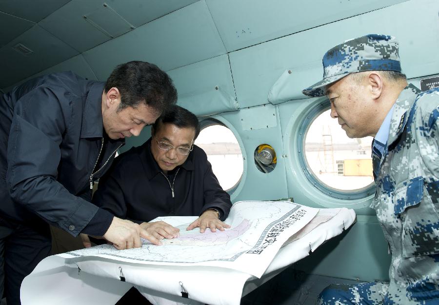 Chinese Premier Li Keqiang (C), also a member of the Standing Committee of the Political Bureau of the Communist Party of China Central Committee, study plans of relief work during his flight on a helicopter heading for the quake-hit Lushan County, southwest China's Sichuan Province, April 20, 2013. Li Keqiang arrived in Sichuan Saturday afternoon to deploy quake relief work. He arrived at Qionglai Airport first and later took a helicopter to the epicenter. (Xinhua/Huang Jingwen)