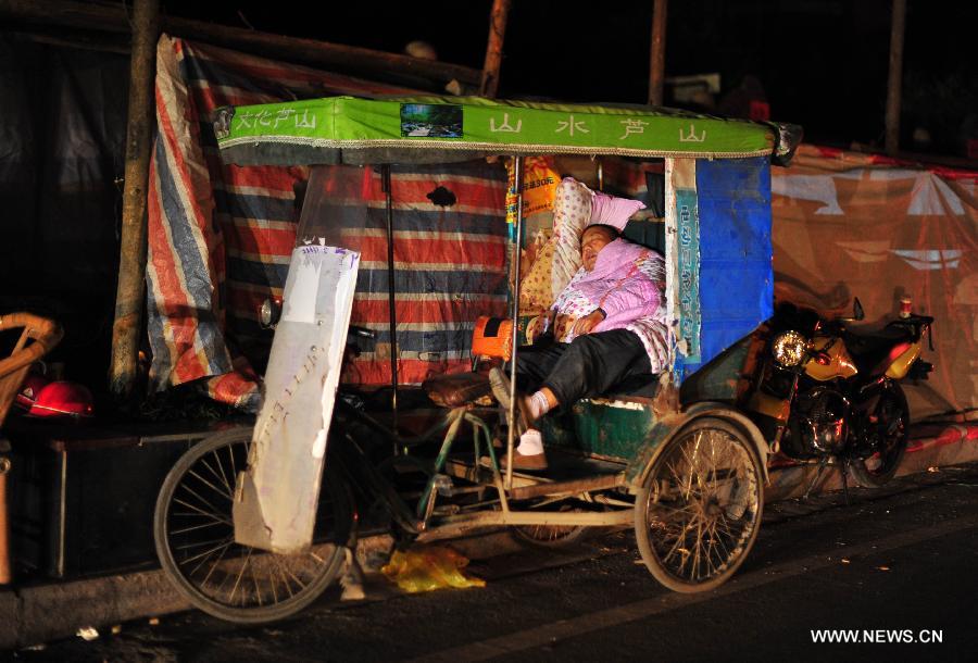 A man sleeps on a tricycle beside a road on the first night after a deadly earthquake in Lushan County, southwest China's Sichuan Province, April 21, 2013. A 7.0-magnitude earthquake jolted Lushan County of Ya'an City on April 20 morning. Many citizens chose to spend the first night after the quake on roads or in temporary tents. (Xinhua/Xiao Yijiu)  