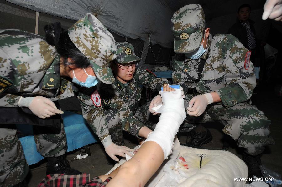 Doctors from the Chengdu Military Region bandage up a foot for a wounded person in a temporary tent outside the Lushan People's Hospital in Lushan County of Ya'an City, southwest China's Sichuan Province, April 21, 2013. A 7.0-magnitude earthquake which hit Lushan County on April 20 morning damaged the Lushan People's Hospital and doctors had to erect temporary tents outside the hosptial to treat the injured people. (Xinhua/Li Jian) 