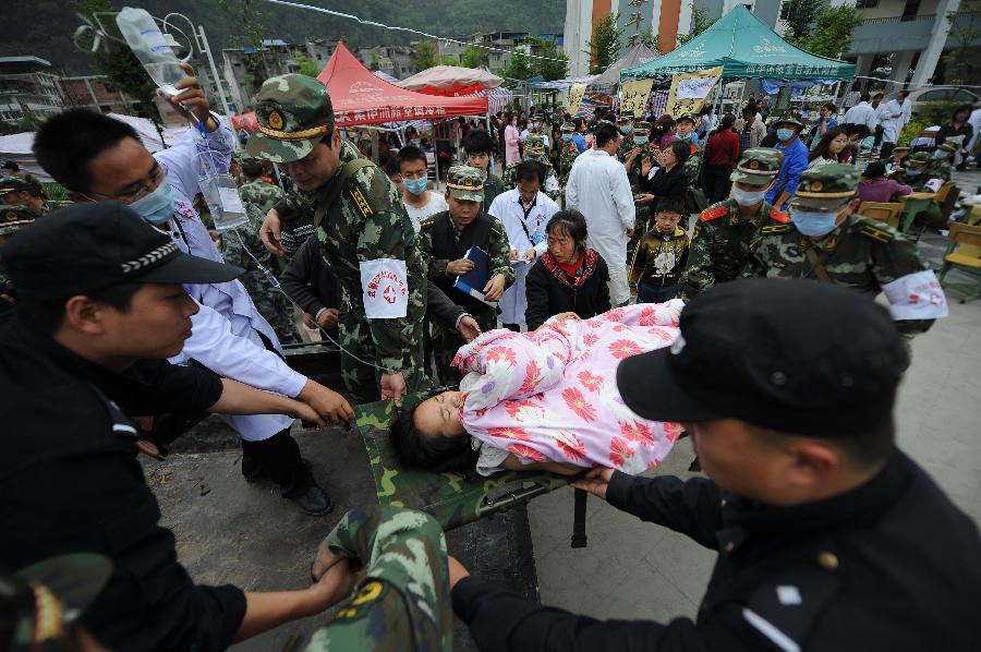 Rescuers transfer an injured person in Lingguan Town of Baoxing County in Ya'an City, southwest China's Sichuan Province, April 21, 2013. A 7.0-magnitude earthquake hit Lushan County of Sichuan Province on Saturday morning, leaving 26 people dead and 2,500 others injured, including 30 in critical condition, in neighboring Baoxing County, county chief Ma Jun said. (Xinhua/Xue Yubin) 