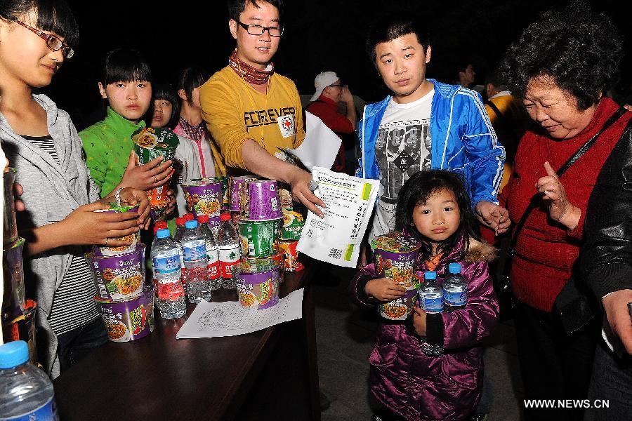 Volunteers of the Red Cross Society of China distribute relief materials to victims in Lushan County of Ya'an City, southwest China's Sichuan Province, April 21, 2013. A 7.0-magnitude earthquake jolted Lushan County on April 20 morning and by now more than 330 medical workers and voluteers from the Red Cross Society conduct relief work in the quake-hit region. (Xinhua/He Junchang)  