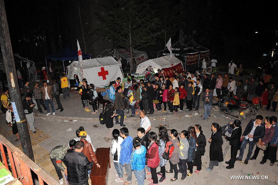 Victims queue to get relief materials from volunteers of the Red Cross Society of China in Lushan County of Ya'an City, southwest China's Sichuan Province, April 21, 2013. A 7.0-magnitude earthquake jolted Lushan County on April 20 morning and by now more than 330 medical workers and voluteers from the Red Cross Society conduct relief work in the quake-hit region. (Xinhua/He Junchang)  