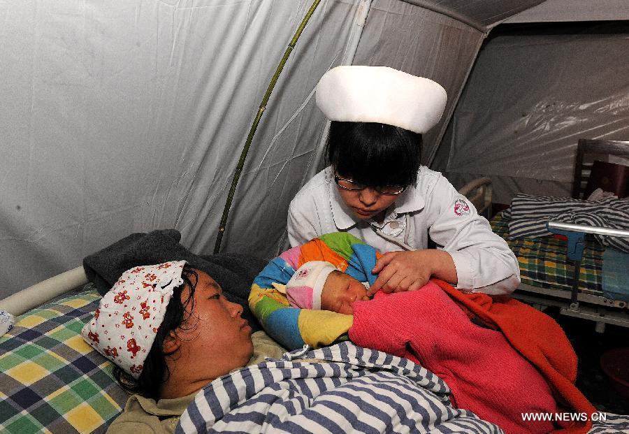 A medical worker of the Red Cross Society of China checks a puerpera and her newborn in a temporary tent in Lushan County of Ya'an City, southwest China's Sichuan Province, April 21, 2013. A 7.0-magnitude earthquake jolted Lushan County on April 20 morning and by now more than 330 medical workers and voluteers from the Red Cross Society conduct relief work in the quake-hit region. (Xinhua/He Junchang)  