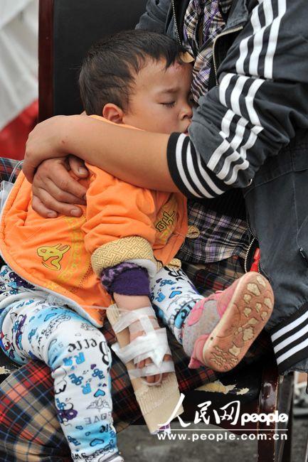 A child getting intravenous infusion sits on the knees of his mother in the People's Hospital in Lushan, Sichuan province, April 21, 2013. More than 3,000 people had been sent here to get treatment as of 11:30 a.m. of April 21, 2013. (Weng Qiyu/People’s Daily Online)
