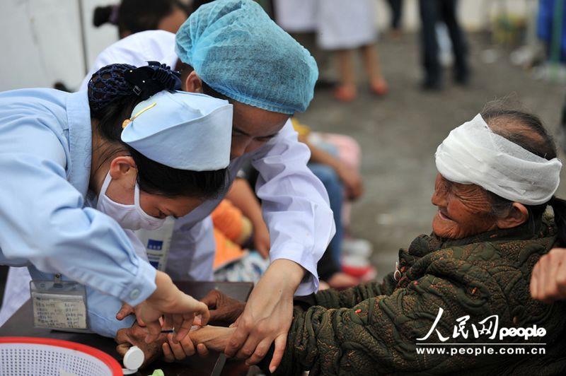 A nurse treats a wounded woman in the People's Hospital in Lushan, Sichuan province, April 21, 2013. More than 3,000 people had been sent here to get treatment as of 11:30 a.m. of April 21, 2013. (Weng Qiyu/People’s Daily Online)