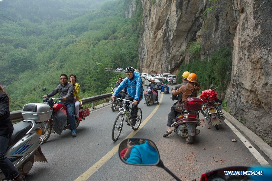 People ride on a road leading to Baosheng Town as stones fall in quake-hit Lushan County in Ya'an City, southwest China's Sichuan Province, April 21, 2013. A 7.0-magnitude earthquake jolted Lushan County on April 20 morning. Aftershocks continued to rock the region. (Xinhua/Chen Cheng) 