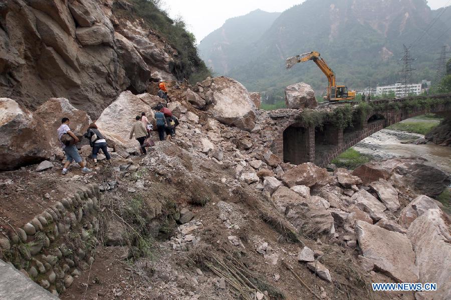 People walk on rocks fallen due to the landslide triggered by a strong quake in Baosheng Township, Lushan County, southwest China's Sichuan Province, April 21, 2013. Death toll has risen to 208 in the earthquake in Sichuan as of 5:00 p.m. Sunday, according to latest statistics gathered by local authorities. A 7.0-magnitude earthquake hit Lushan County at 8:02 a.m. Saturday Beijing time. (Xinhua/Zhang Xiaoli) 