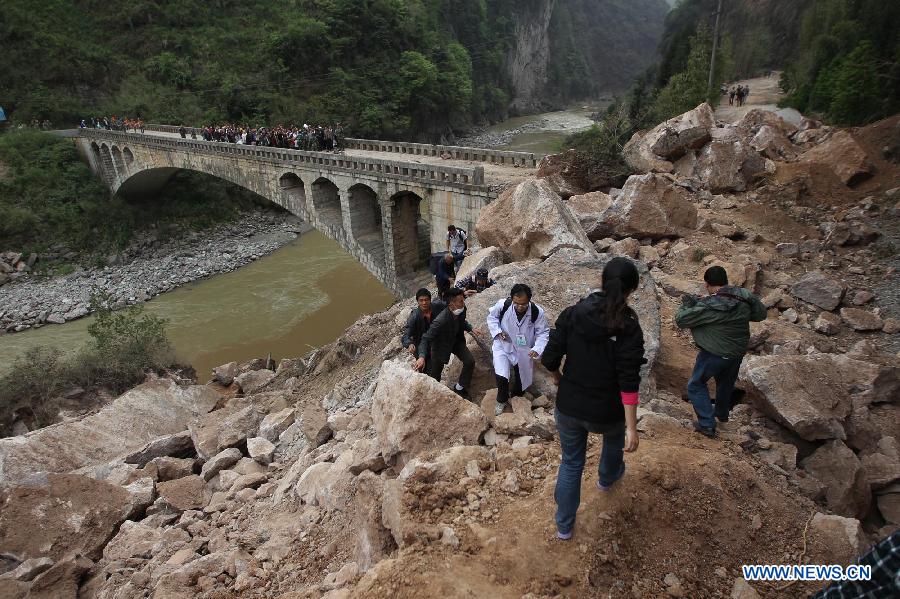 People walk on rocks fallen due to the landslide triggered by a strong quake in Baosheng Township, Lushan County, southwest China's Sichuan Province, April 21, 2013. Death toll has risen to 208 in the earthquake in Sichuan as of 5:00 p.m. Sunday, according to latest statistics gathered by local authorities. A 7.0-magnitude earthquake hit Lushan County at 8:02 a.m. Saturday Beijing time. (Xinhua/Zhang Xiaoli) 