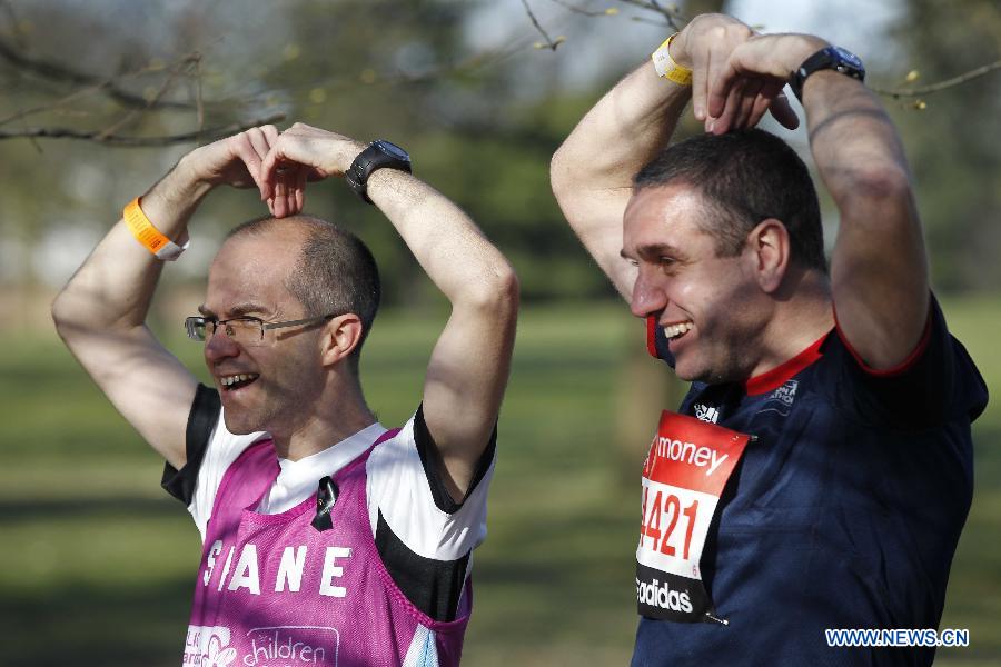 A competitor gestures for photos with a member of staff before the start of the London Marathon in Greenwich, London, capital of Britain, on April 21, 2013. (Xinhua/Yin Gang)