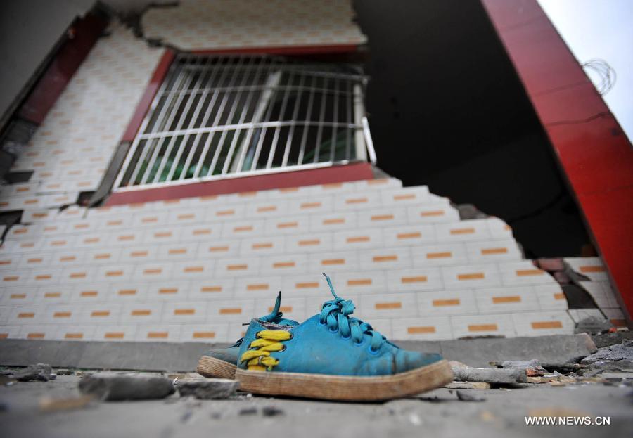 A shoe is left next to a damaged house in Baosheng Township, Lushan County, southwest China's Sichuan Province, April 21, 2013. Baosheng Township is another seriously affected area in Lushan. Search and rescue work continued here Sunday, and the work for restoring roads and communications are conducted in the pipelines. (Xinhua/Xiao Yijiu)