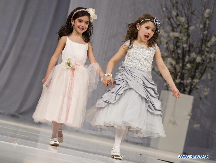 Two girls present young bridesmaid's dresses during the fashion show of the 2013 Toronto's Bridal Show at the Canadian National Exhibition in Toronto, Canada, April 21, 2013.(Xinhua/Zou Zheng) 