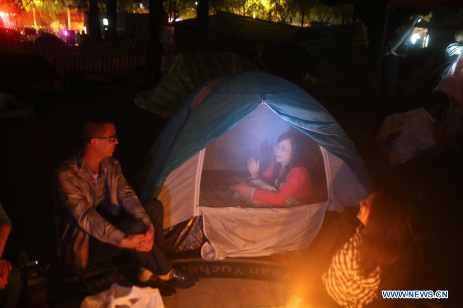 A man chats with a woman in a tent at a temporary settlement at the playground of a primary school in quake-hit Ya'an City, southwest China's Sichuan Province, April 21, 2013. A 7.0-magnitude earthquake jolted Lushan County of Ya'an City on April 20 morning. (Xinhua/Xing Guangli) 
