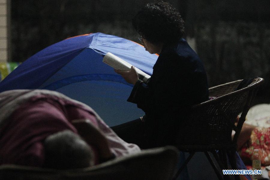 A citizen reads beside a tent at a temporary settlement at the playground of a primary school in quake-hit Ya'an City, southwest China's Sichuan Province, April 21, 2013. A 7.0-magnitude earthquake jolted Lushan County of Ya'an City on April 20 morning. (Xinhua/Xing Guangli) 
