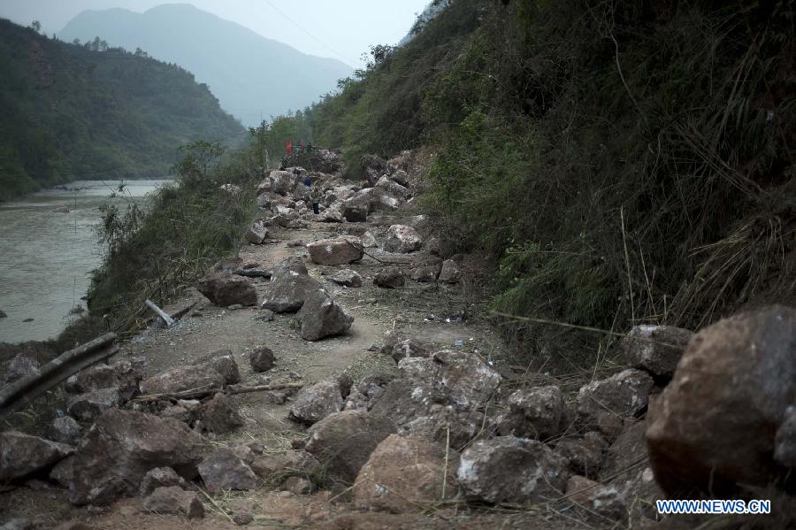 Residents try to pass through a road blocked by fallen rocks due to the landslide in the quake-hit Baosheng Township, Lushan County, southwest China's Sichuan Province, April 21, 2013. Baosheng Township is another seriously affected area in Lushan. Search and rescue work continued here Sunday, and the work for restoring roads and communications are conducted in the pipelines. (Xinhua/Fei Maohua)