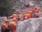 Rescuers try to pass through a road blocked by fallen rocks