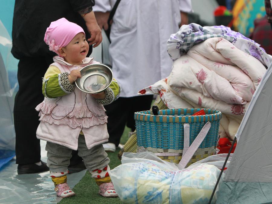 One-and-a-half-year-old Wang Xiuhan waits for lunch at a temporary settlement in the quake-hit Baoxing County, southwest China's Sichuan Province, April 22, 2013. (Xinhua/Pei Xin)