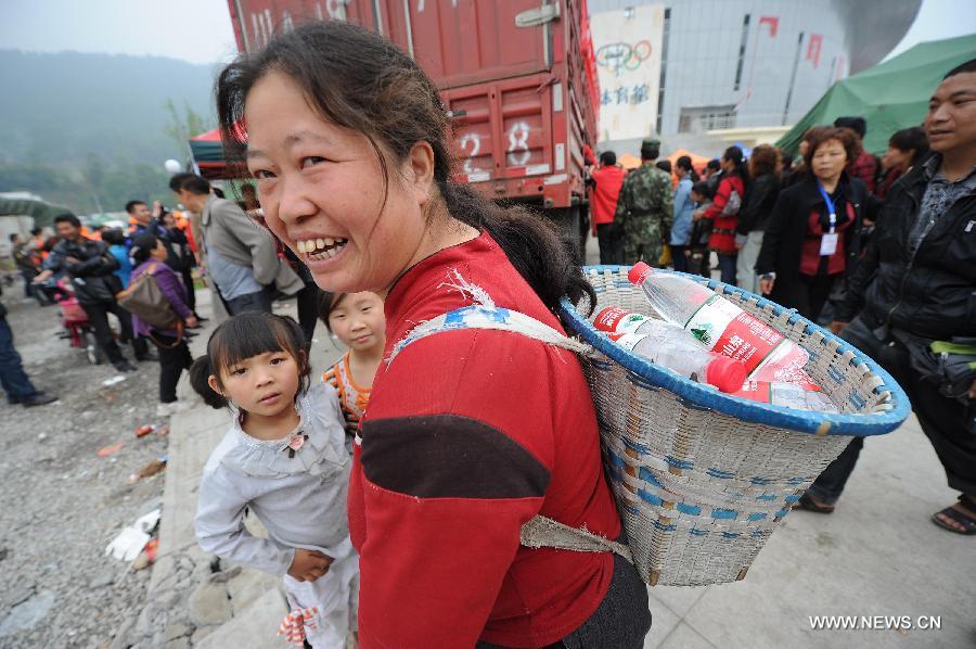 A woman carries bottles of water at a temporary settlement site in the quake-hit Lushan County, southwest China's Sichuan Province, April 22, 2013. The water and power supply were suspended after a 7.0-magnitude earthquake jolted Lushan County on April 20 morning. Rescue organizations are using water purification equipment to provide drinking water for affected local residents. (Xinhua/Li Jian)