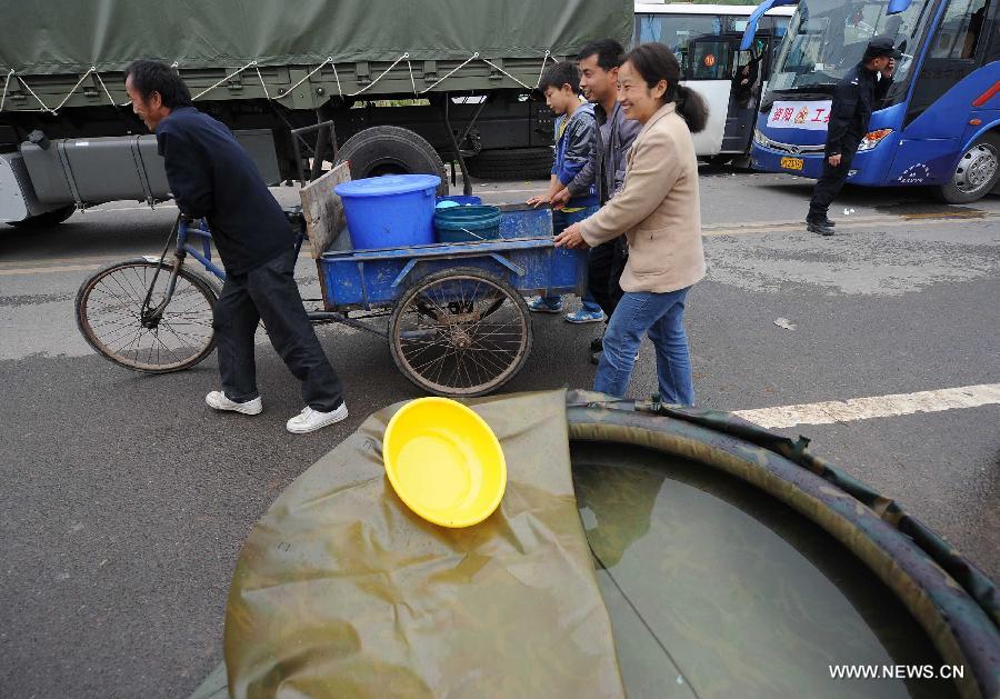 People carry drinking water to a temporary settlement site in the quake-hit Lushan County, southwest China's Sichuan Province, April 22, 2013. The water and power supply were suspended after a 7.0-magnitude earthquake jolted Lushan County on April 20 morning. Rescue organizations are using water purification equipment to provide drinking water for affected local residents. (Xinhua/Li Jian)