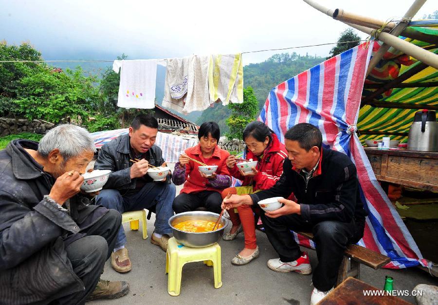 Villagers have lunch in Yuxi Primary School served as an evacuation settlement in the quake-hit Yuxi Village, Baosheng Township, Lushan County in southwest China's Sichuan Province, April 22, 2013. Over 40 displaced villagers lived in makeshift tents in the settlement where they helped each other to overcome difficulties together. (Xinhua/Xiao Yijiu)