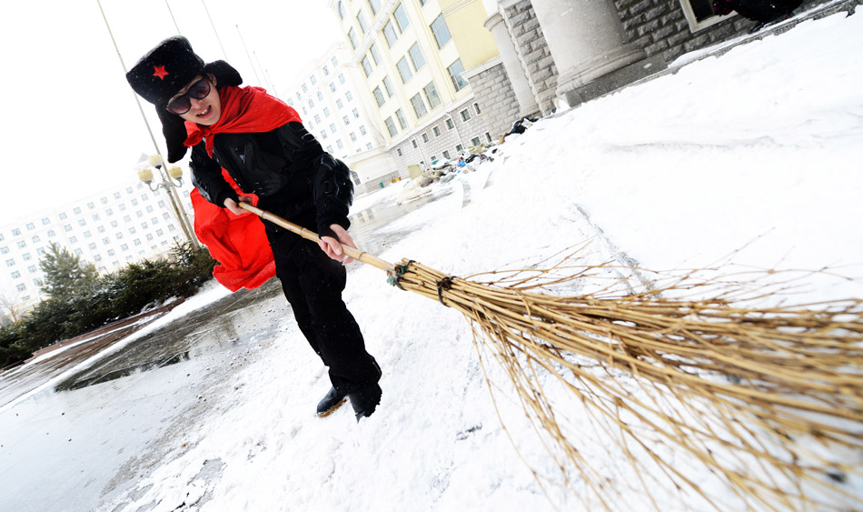 Xue Fei, dressed in costume of "Lei Feng Man" cleans the snow in front of the Art Department of Heilongjiang University, April 14, 2013. Influenced by the hot micro movie "Lei Feng Man", Xue, a student of Heilongjiang University, has imitated the movie's hero to help others since 2011. (Xinhua/Wang Kai)  