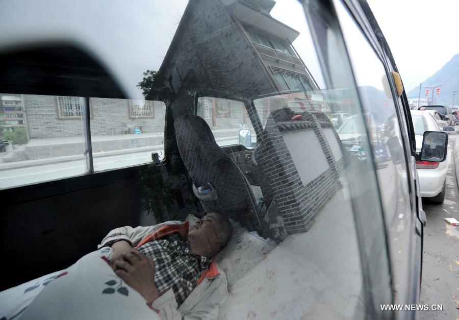A man sleeps in his vehicle in quake-hit Baoxing County of Ya'an City, southwest China's Sichuan Province, April 23, 2013. A 7.0-magnitude earthquake jolted Lushan County of Ya'an City on April 20. (Xinhua/Luo Xiaoguang)  