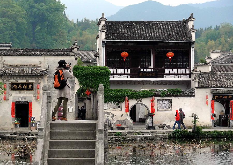 A tourist takes photos on a stone arch bridge at the Nanhu Scenic Spot of Hongcun Village in Yixian County, east China's Anhui Province, April 21, 2013. (Xinhua/Wang Song) 
