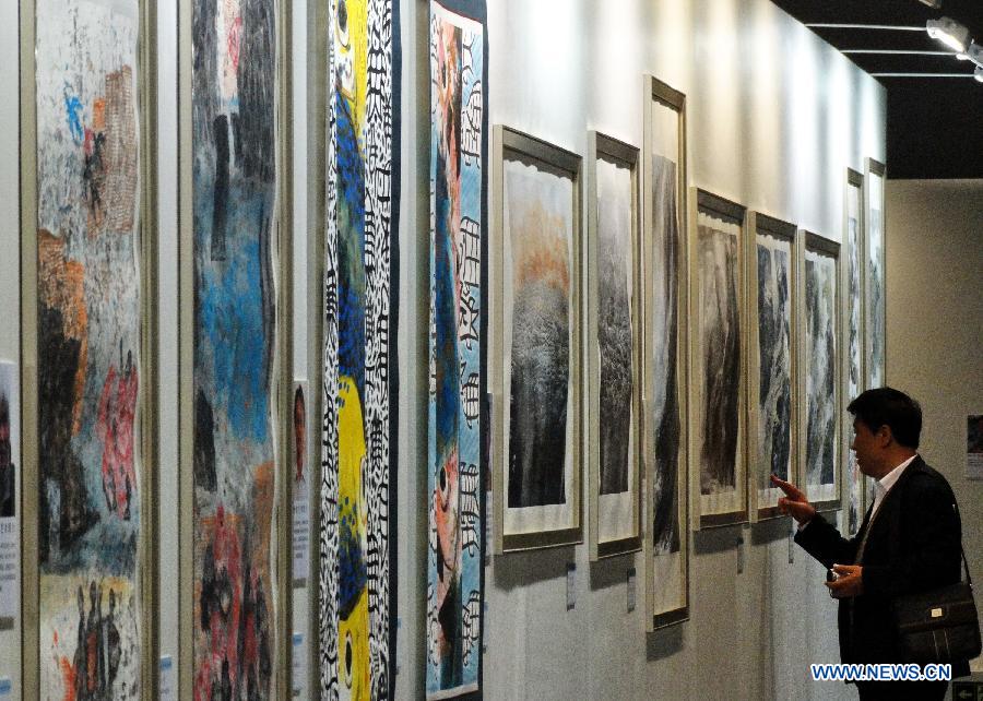 A visitor watches paintings at an art exhibition themed on Chinese ocean in Beijing, capital of China, April 24, 2013. Over 130 pieces of artworks are on display. (Xinhua/Li Xin)