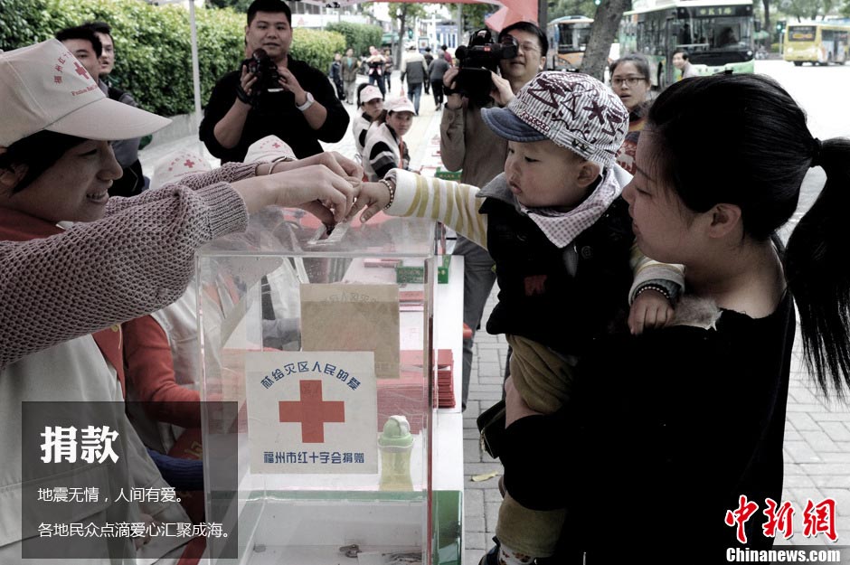 Fuzhou resident Chen Lixing holding his one-year-old son in arms makes donation at a donation spot of Fuzhou Red Cross on April, 21. (Photo/CNS)