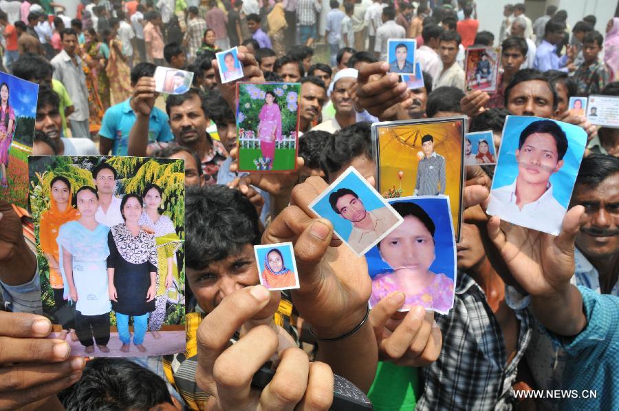 People show photos of their relatives during rescuers' operation in the collapsed Rana Plaza building in Dhaka, Bangladesh, April 25, 2013. Rescue workers continued their struggle Thursday to reach many more who are feared trapped in the rubble one day after a building collapse in Savar on the outskirts of Bangladesh's capital Dhaka, with the death toll rising to 195. (Xinhua/Shariful Islam) 