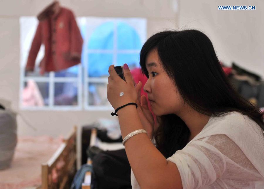 A girl puts up makeup in a tent at a temporary settlement for quake-affected people in Lushan Middle School in Lushan County, southwest China's Sichuan Province, April 26, 2013. A 7.0-magnitude jolted Lushan County on April 20. (Xinhua/Li Wen) 