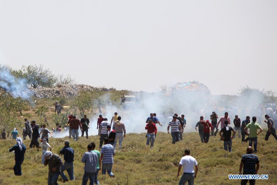 Palestinian protesters take cover of gas fired by Israeli soldiers during clashes after a protest against settlement's expansion and settlers attack in the west bank village of Dir Jrer near Ramallah on April 26, 2013. Six protesters were injured during clashes between Palestinians and Israeli soldiers. (Xinhua/Fadi Arouri)