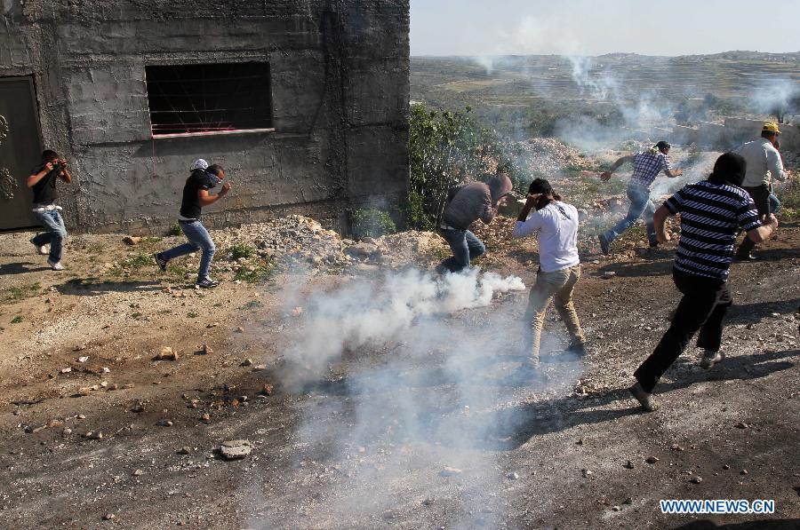 Palestinian protesters run to take cover of gas fired by Israeli soldiers during a protest against the expanding of Jewish settlements in Kufr Qadoom village near the West Bank city of Nablus on April 26, 2013. (Xinhua/Ayman Nobani)