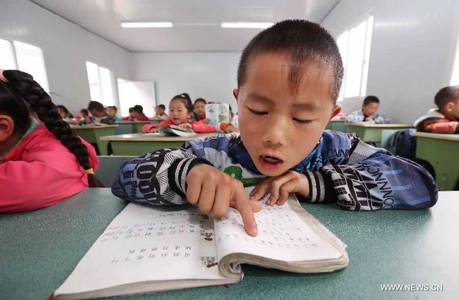 A boy reads textbook in Baosheng Primary School in Lushan County, southwest China's Sichuan Province, April 26, 2013. The primary school was built within 28 hours by the air force troops from the People's Liberation Army (PLA) Chengdu Military Area Command (MAC), who also donated stationery and computers to students and teachers affected by the earthquake which hit Lushan County on April 20. (Xinhua/Liu Yinghua)