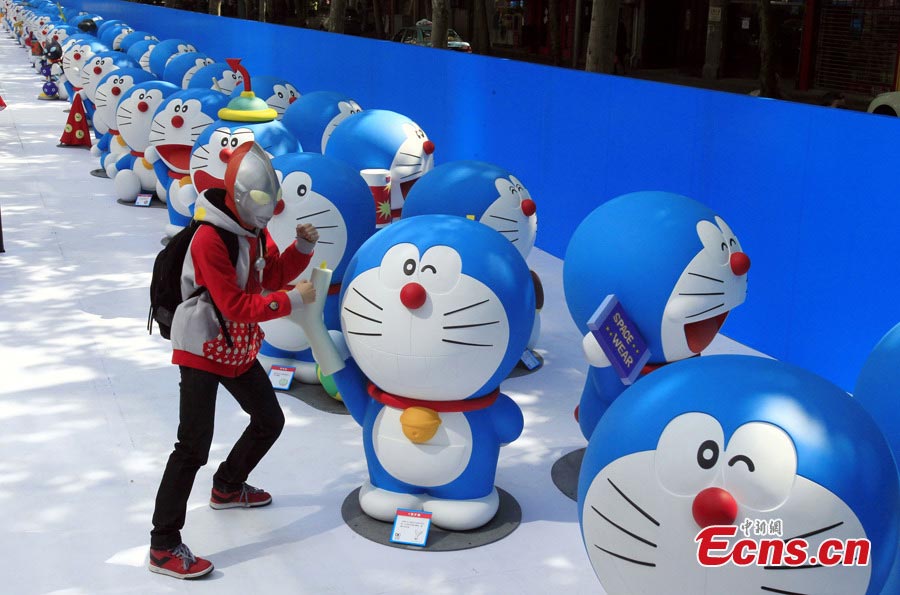 A visitor poses with Doraemon, a robot cat in a Japanese animation series, at Xintiandi in Shanghai, April 26, 2013. An exhibition featuring 100 Doraemons with 100 different gadgets and machines it used in the series is being held at Xintiandi until June 16. It is the largest exhibition featuring Doraemon on the Chinese mainland. (CNS/Pan Suofei)