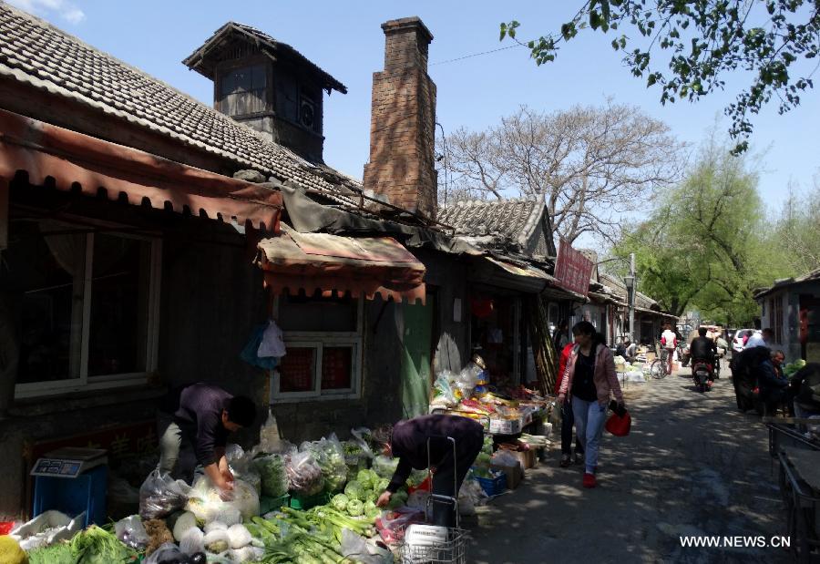 Local residents purchase vegetables in a hutong market located in Dongcheng District in Beijing, capital of China, April 27, 2013. Local administration has taken a series of measures to protect Hutong, ancient architecture and courtyards in Dongcheng District, including renovation and putting up brands with Chinese-English bilingual introduction for old buildings. (Xinhua/Li Xin)  