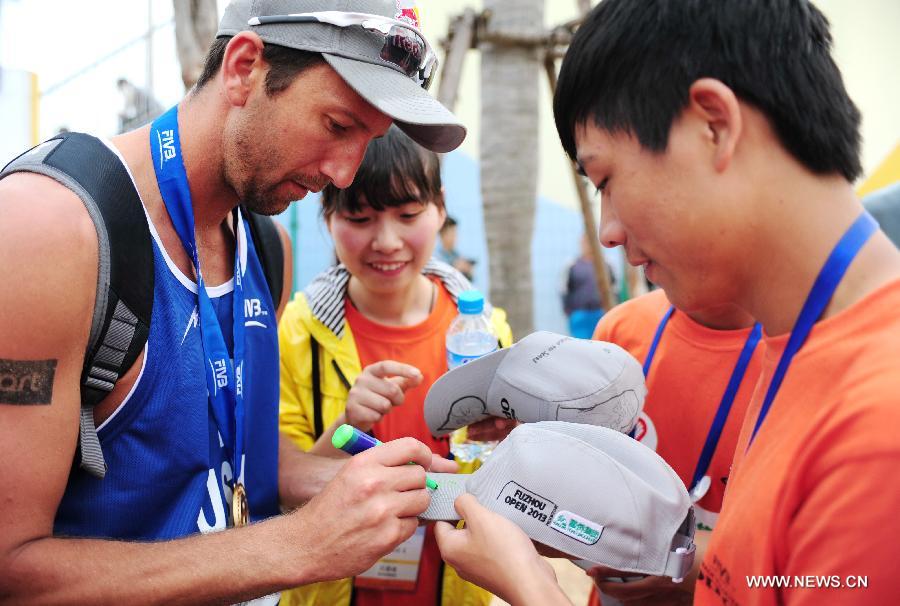 Sean Rosenthal (L) of the United States signs for fans after the men's final of the Fuzhou Open, the beginning of the 2013 beach volleyball season, in Fuzhou, southeast China's Fujian province, April 27, 2013. Sean Rosenthal and Philip Dalhausser from the United States won the final 2-0 to claim the title of the event. (Xinhua/Lin Shanchuan)