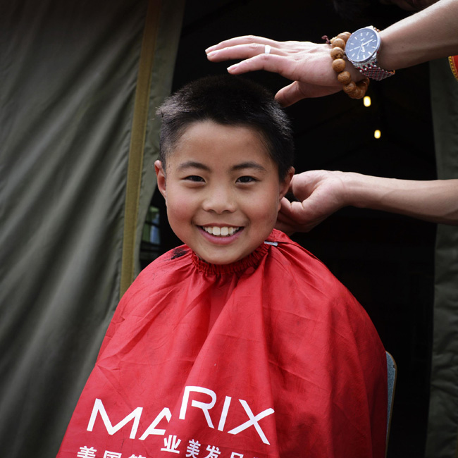 Nine-year-old Yang Zongce gets a hair cut in a resettlement site for earthquake victims in Lushan county, Southwest China's Sichuan province. Photo taken on April 25. The Lushan earthquake on April 20 killed nearly 200 people and left a lot more including children homeless. Today is the World Children's Day, which falls on the fourth Sunday of April every year, let's wish for good luck for the children who have been affected by the quake. [Photo/Xinhua]