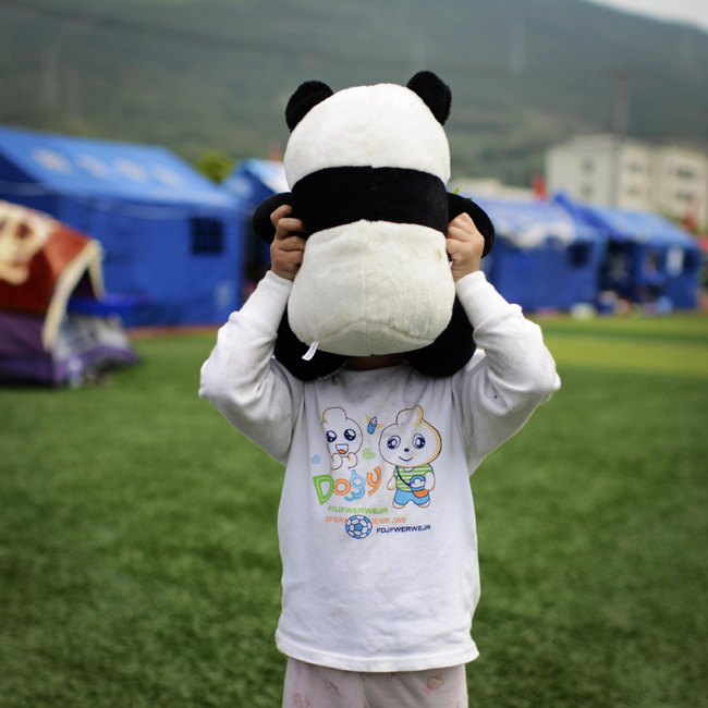 Zhang Yiyin, three and a half years old, plays with a panda toy in a resettlement site for earthquake victims in Lushan county, Southwest China's Sichuan province. Photo taken on April 25. [Photo/Xinhua]