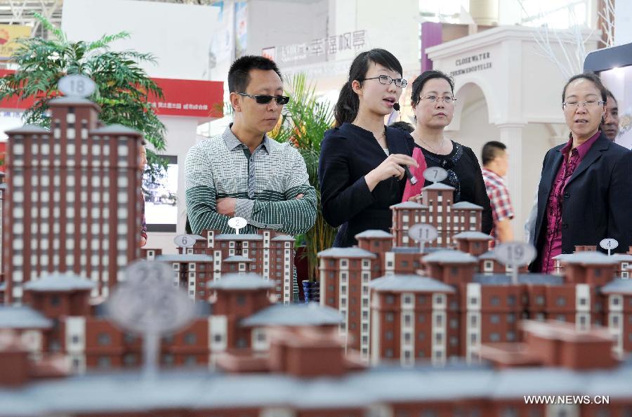 Visitors learn housing information in front of the model of a residential housing project during the 5th Western China House and Automobile Fair in Yinchuan, capital of northwest China's Ningxia Hui Autonomous Region, April 28, 2013. The 7-day fair, which kicks off on April 28, attracted 30 property developers and 54 automakers. (Xinhua/Peng Zhaozhi) 