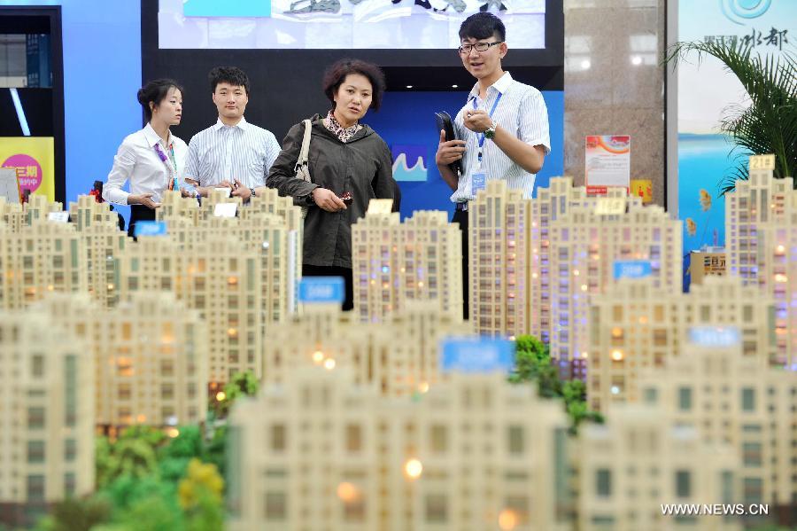 A visitor learns housing information in front of the model of a residential housing project during the 5th Western China House and Automobile Fair in Yinchuan, capital of northwest China's Ningxia Hui Autonomous Region, April 28, 2013. The 7-day fair, which kicks off on April 28, attracted 30 property developers and 54 automakers. (Xinhua/Peng Zhaozhi) 