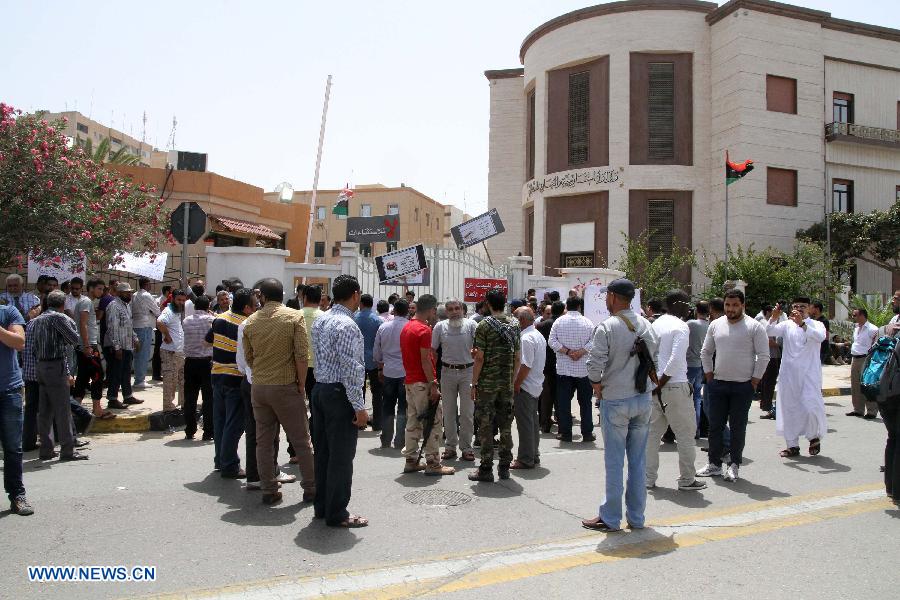 People surround the Foreign Ministry of Libya during a rally in Tripoli, April 28, 2013. Dozens of gunmen on Sunday surrounded Libya's foreign ministry in downtown Tripoli to demand a ban against those working under the former regime from holding senior positions. The gunmen, who claimed to have come from across the country, blocked the main streets near the foreign ministry using heavy weapons and military trucks. (Xinhua/Hamza Turkia)